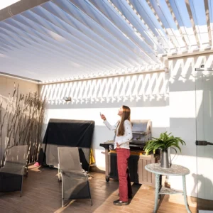 Pérgola bioclimática blanca sobre quincho con parrilla en terraza residencial